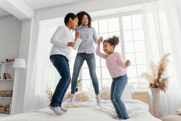 Smileymoeder die in bed thuis met haar kinderen springt