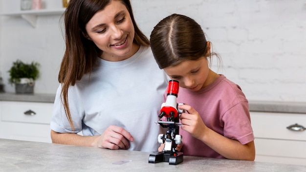 Smileymoeder en dochter die experimenten met microscoop doen