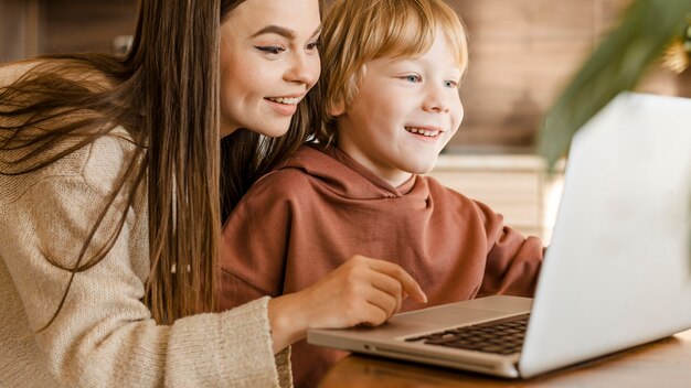 Smileymoeder en kind die laptop samen met behulp van