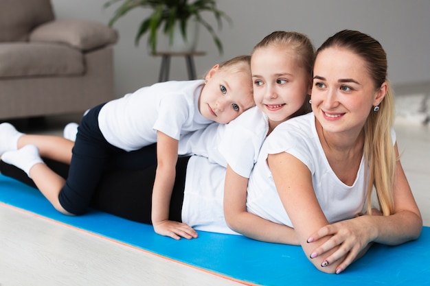 Gratis foto smileymoeder het stellen met gelukkige dochters thuis op yogamat