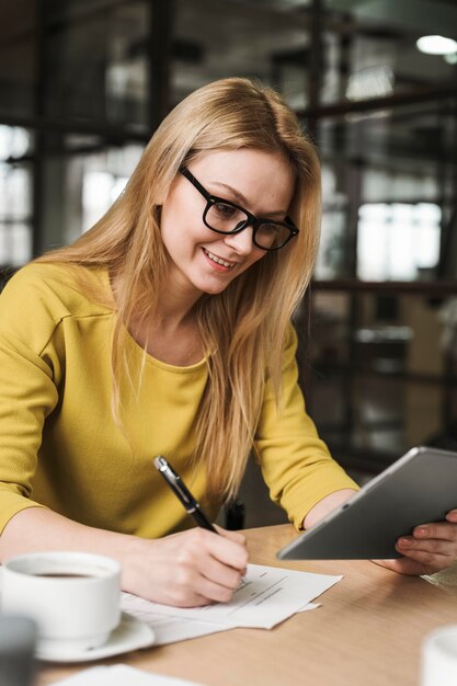 Smileyonderneemster met glazen die bij bureau werken