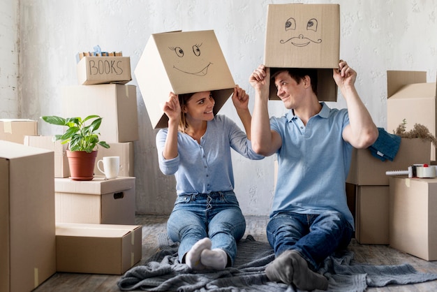 Smileypaar thuis op verhuisdag met dozen boven het hoofd