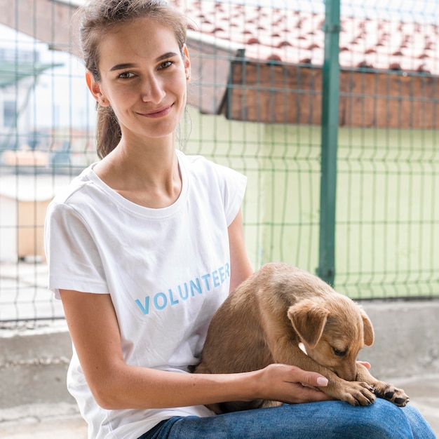 Gratis foto smileyvrouw bij dierenasiel die hond vasthoudt voor goedkeuring