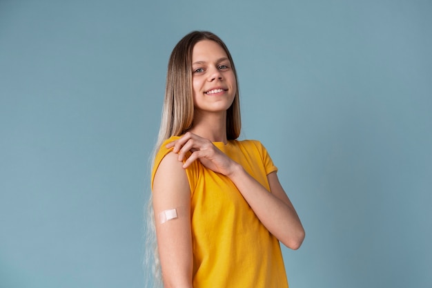 Smileyvrouw die arm met sticker toont na het krijgen van een vaccin