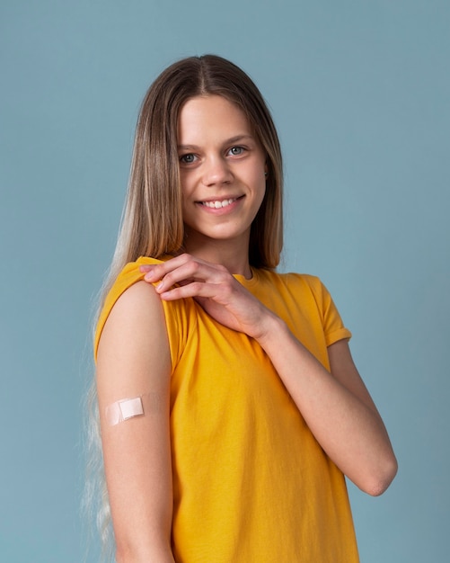 Smileyvrouw die arm met sticker toont na het krijgen van een vaccin