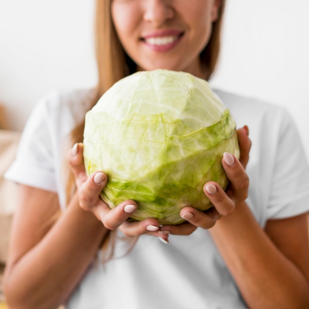 Gratis foto smileyvrouw die een groene kool houdt