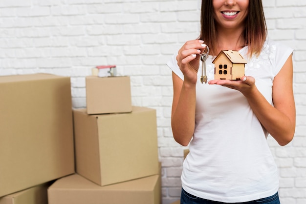 Smileyvrouw die een houten plattelandshuisje en sleutels houden