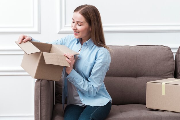 Smileyvrouw die een pakket binnen houden en op laag zitten