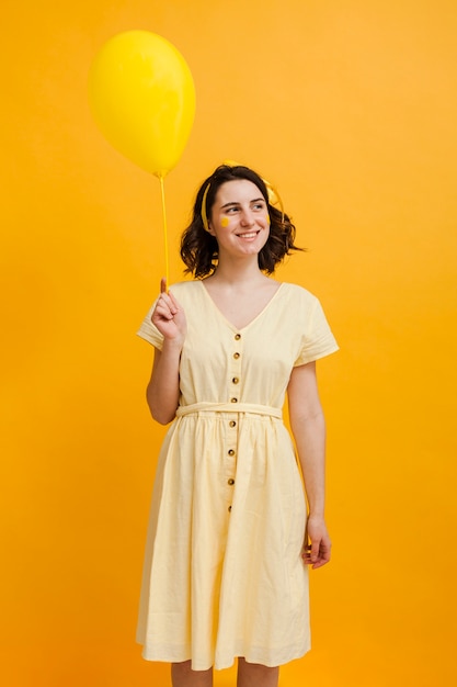 Gratis foto smileyvrouw die gele ballon houden