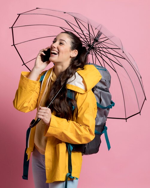 Smileyvrouw die op de telefoon spreken terwijl het houden van een paraplu