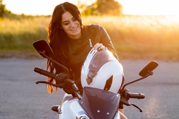 Gratis foto smileyvrouw die op haar motorfiets rust
