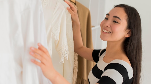 Gratis foto smileyvrouw die op kleren proberen