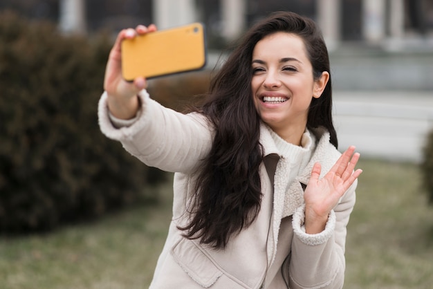 Gratis foto smileyvrouw die selfie in openlucht nemen