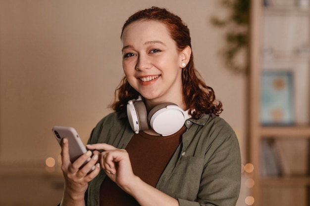 Smileyvrouw die smartphone en hoofdtelefoons gebruikt