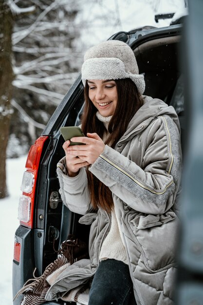 Smileyvrouw die smartphone uit de auto gebruikt tijdens een roadtrip