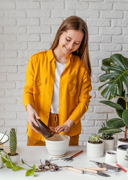 Gratis foto smileyvrouw die thuis tuinieren