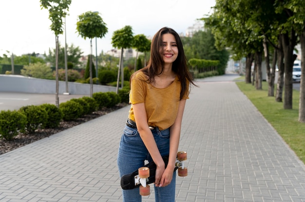 Smileyvrouw in de stad die skateboard houdt