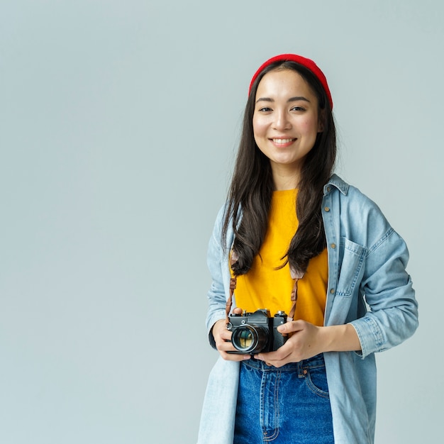 Gratis foto smileyvrouw met camera binnen