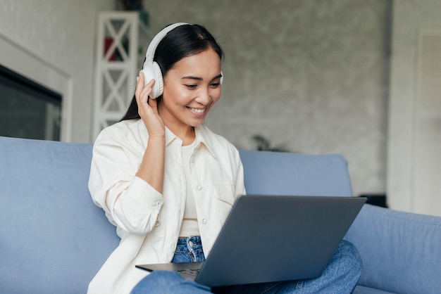 Smileyvrouw met hoofdtelefoons die aan laptop werken