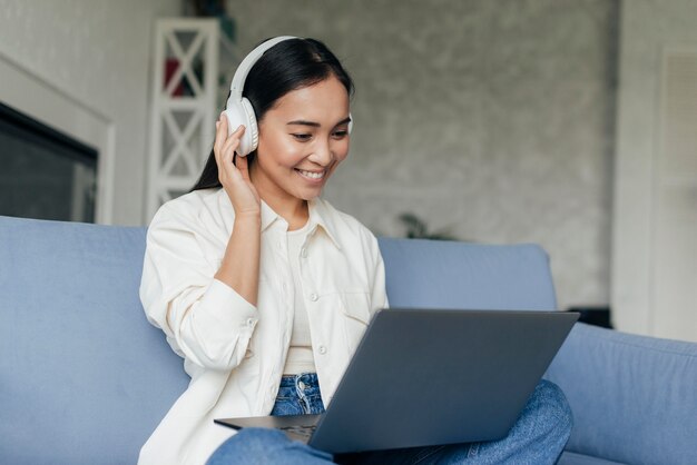 Smileyvrouw met hoofdtelefoons die aan laptop werken