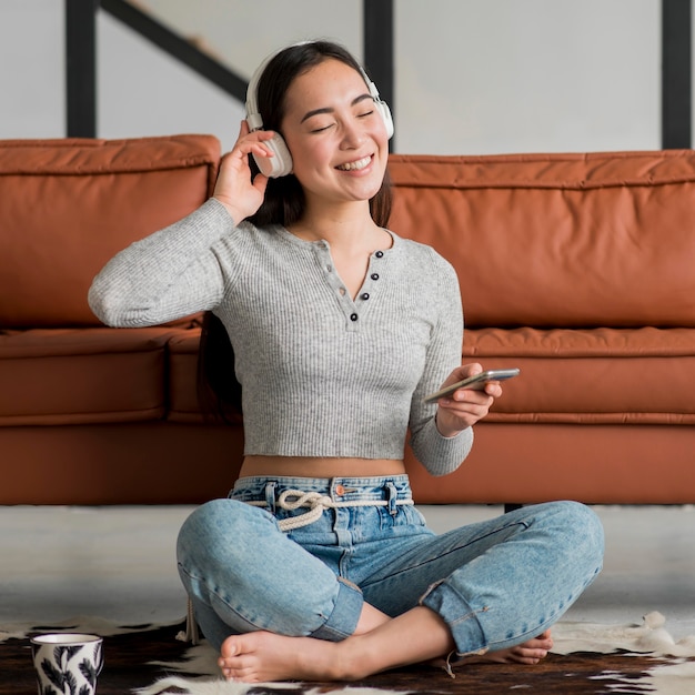 Gratis foto smileyvrouw met hoofdtelefoons het luisteren muziek