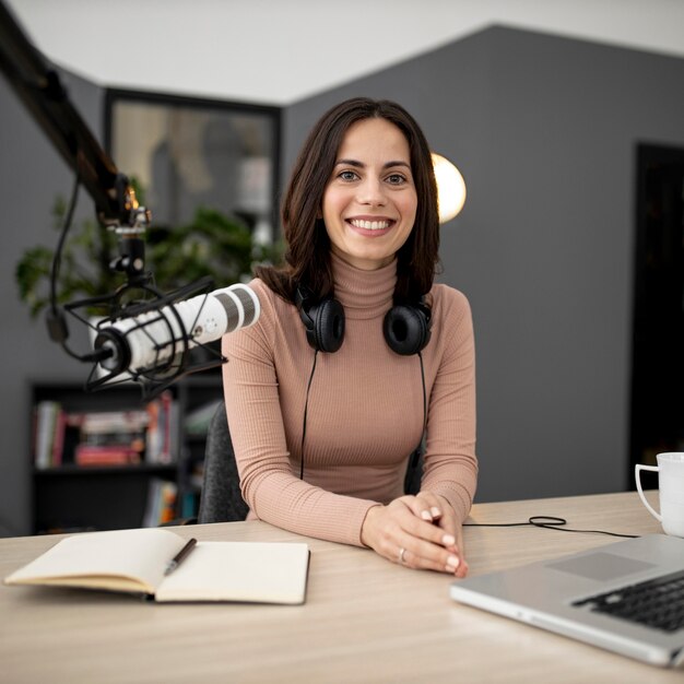 Smileyvrouw met microfoon en notitieboekje in een radiostudio