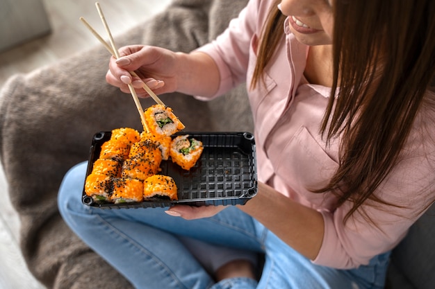 Gratis foto smileyvrouw met sushi bestelt hoge hoek