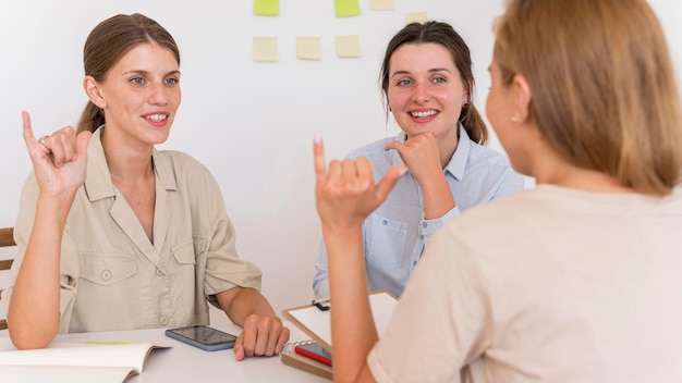 Smileyvrouwen die aan tafel praten met gebarentaal