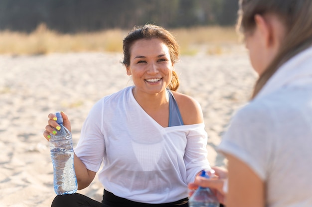 Smileyvrouwen die gehydrateerd blijven tijdens het sporten op het strand