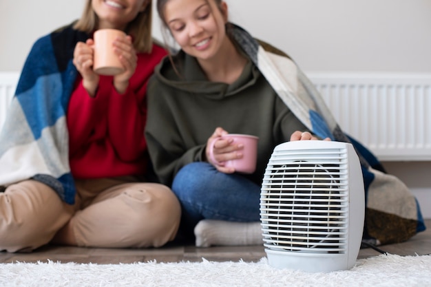 Smileyvrouwen met koffiekopjes dichtbij verwarmer