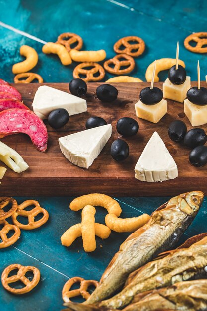 Snack bord met plakjes worst, kaasblokjes en zwarte olijven met crackers en droge vis