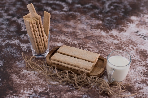 Snacks en crackers in houten schotel met een glas melk, hoekmening.