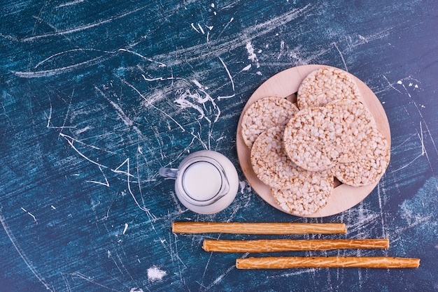 Snacks en crackers op een houten schotel met een potje melk, bovenaanzicht.