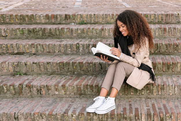 Gratis foto snak schot krullende vrouw die een boek leest