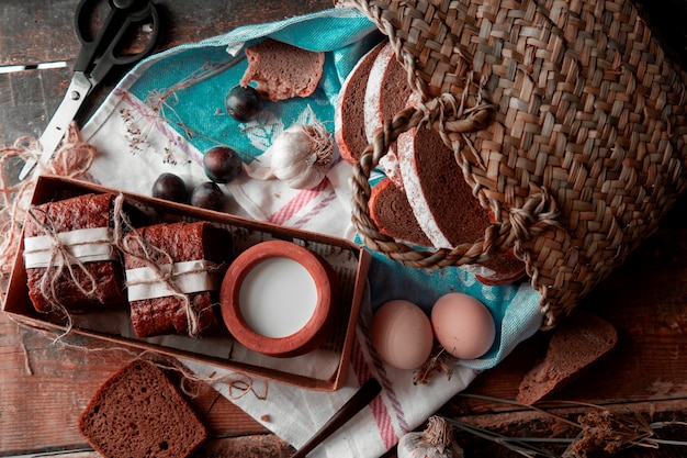 Sneetjes brood gewikkeld met wit papier en draad, melkpot in een boc, mand rond. Bovenaanzicht.