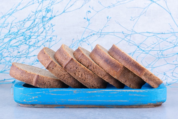 Gratis foto sneetjes bruin brood op een blauwe schotel op marmeren oppervlak