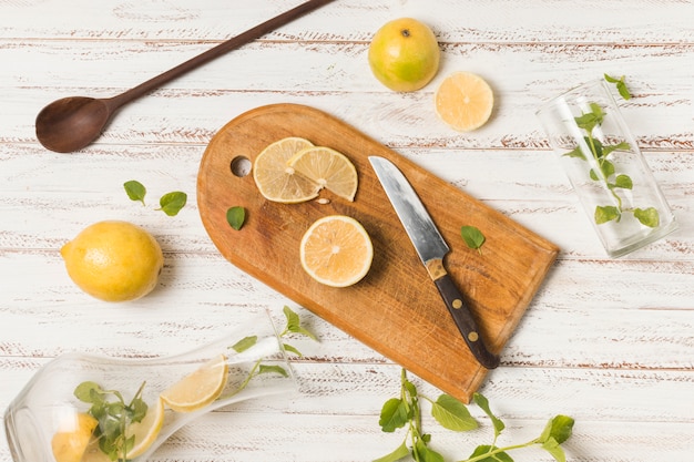 Sneetjes fruit in de buurt van mes tussen kruiden en glazen