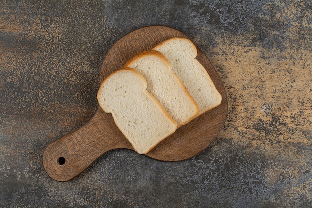 Sneetjes wit toastbrood op houten snijplank.