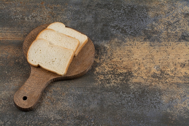 Gratis foto sneetjes wit toastbrood op houten snijplank.