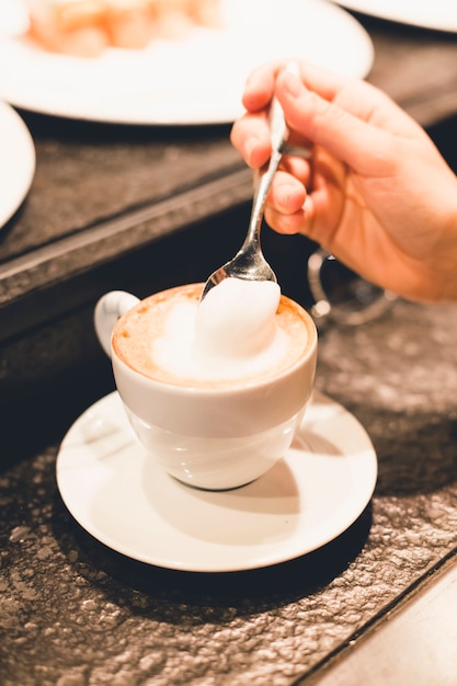 Gratis foto snijd de hand in met schuim van de koffie