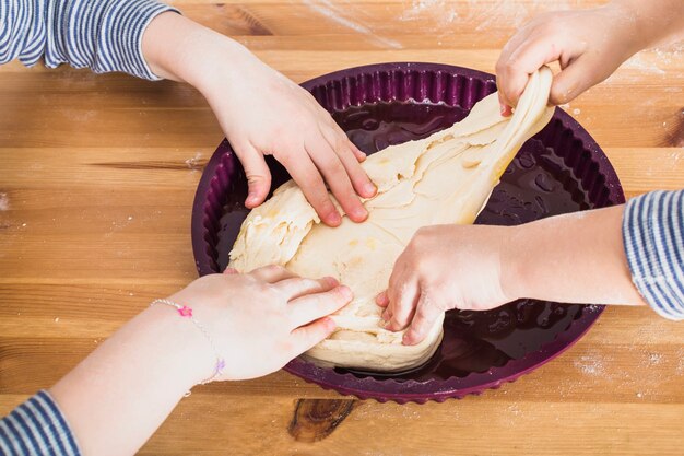 Snijd de handen van kinderen die het deeg in de mal doen