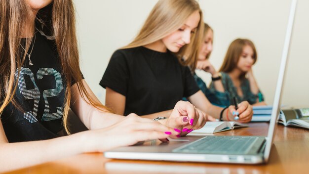 Snijd tiener met behulp van laptop in de buurt van vrienden