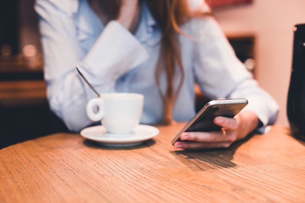 Snijd vrouw het doorbladeren smartphone in koffie