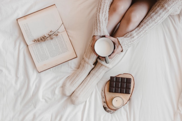 Snijd vrouw met melk dichtbij boek en chocolade