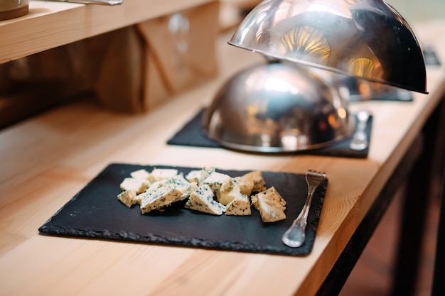 Snijden kaas op een metalen kom met een dop. ontbijt in het hotel of restaurant.