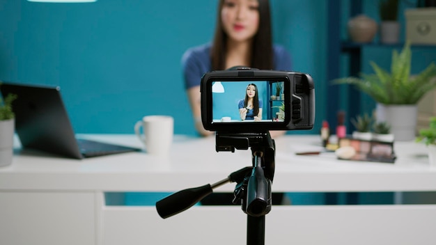 Social media blogger filmt productbeoordeling met camera in studio, met behulp van professionele streamingapparatuur. Vrouwelijke vlogger die lippenstiftcosmetica aanbeveelt voor schoonheidszelfstudie op kanaal. Detailopname.