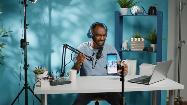 Social media blogger geeft slecht nieuws op camera voor vlog, smartphone gebruikt om video op te nemen. Gefrustreerde vlogger die boos is na het bekijken van een mobiele telefoon en het filmen van podcast voor kanaal