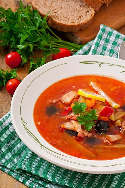 Gratis foto soep solyanka rus met vlees, olijven en augurken in houten kom