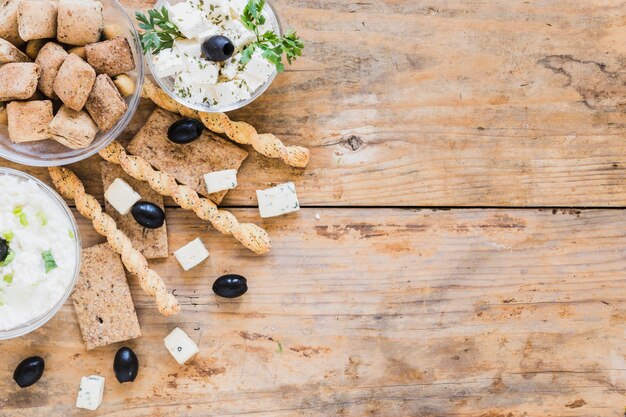 Gratis foto soepstengels, olijven, knapperig brood en gebak met kaas kom op houten tafel