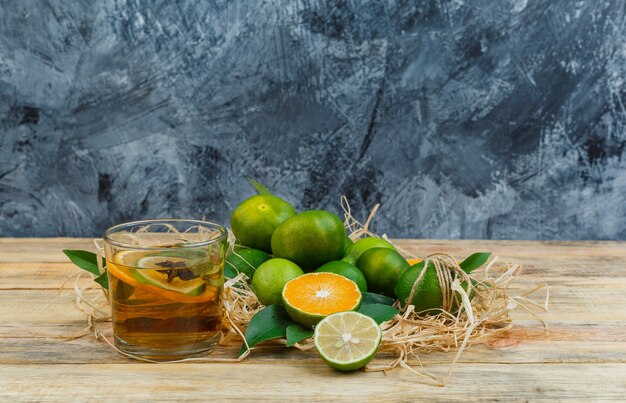 Sommige mandarijnen met een kopje thee op blauw marmer en een houten plank